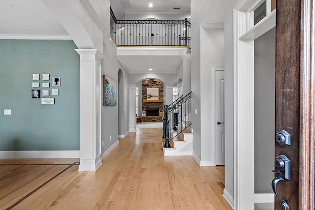 entrance foyer featuring light hardwood / wood-style floors, a towering ceiling, and crown molding