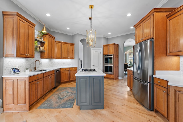 kitchen with sink, light hardwood / wood-style flooring, pendant lighting, a kitchen island, and appliances with stainless steel finishes