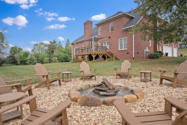 back of property featuring a fire pit, a lawn, and a wooden deck