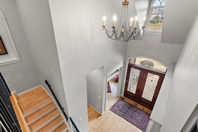 foyer featuring a chandelier, french doors, a high ceiling, and light hardwood / wood-style flooring