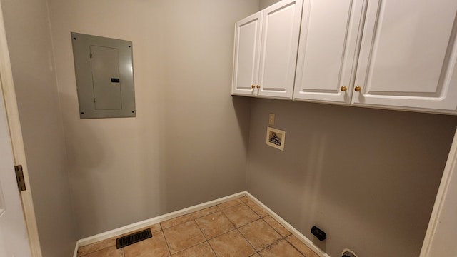 clothes washing area featuring electric panel, hookup for a washing machine, light tile patterned flooring, and cabinets