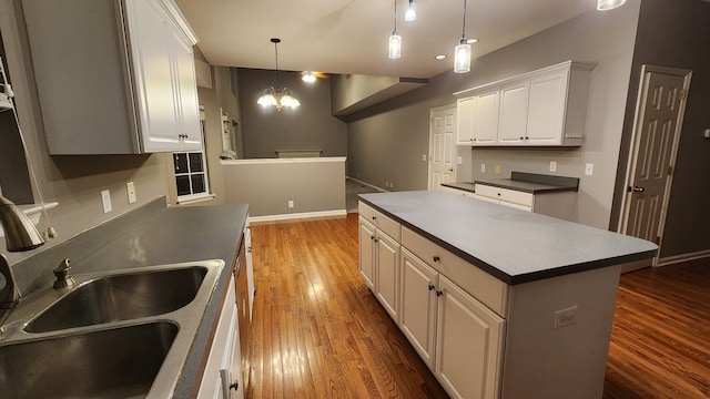 kitchen with dark hardwood / wood-style flooring, pendant lighting, a notable chandelier, white cabinets, and a kitchen island