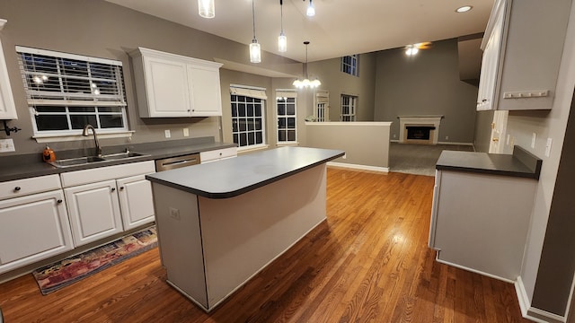 kitchen featuring dark wood-type flooring, sink, a center island, white cabinetry, and hanging light fixtures