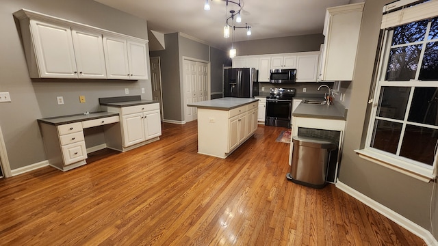 kitchen featuring pendant lighting, sink, light hardwood / wood-style floors, appliances with stainless steel finishes, and a kitchen island