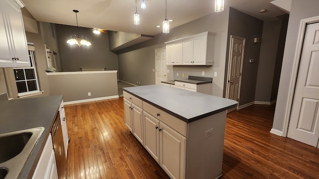 kitchen with pendant lighting, dark hardwood / wood-style floors, a notable chandelier, a kitchen island, and white cabinetry