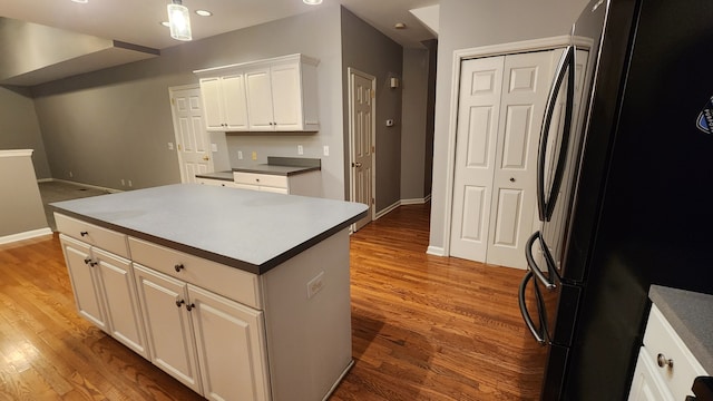 kitchen featuring white cabinetry, a center island, refrigerator, and hardwood / wood-style flooring