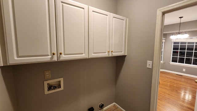 washroom with a notable chandelier, cabinets, light wood-type flooring, and washer hookup