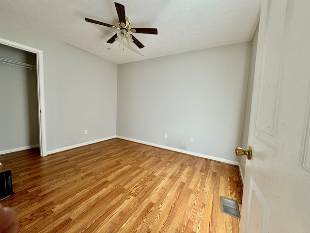 unfurnished bedroom with wood-type flooring, a textured ceiling, a closet, and ceiling fan