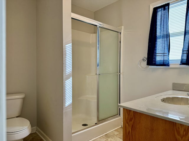 bathroom with a shower with door, vanity, a healthy amount of sunlight, and toilet