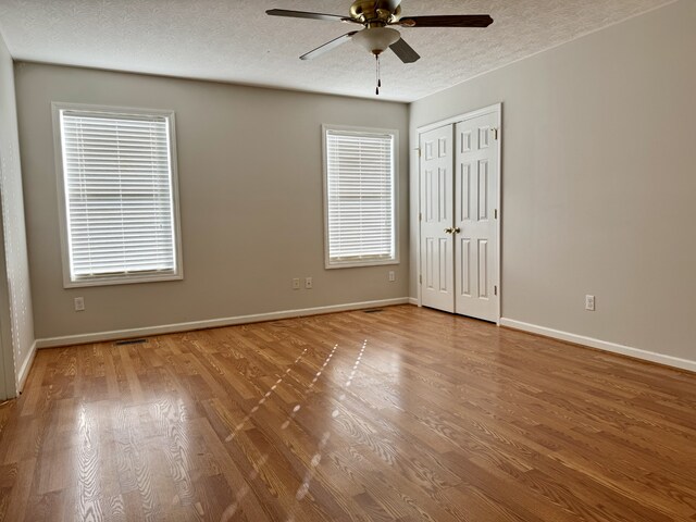 unfurnished room featuring hardwood / wood-style floors, plenty of natural light, ceiling fan, and a textured ceiling