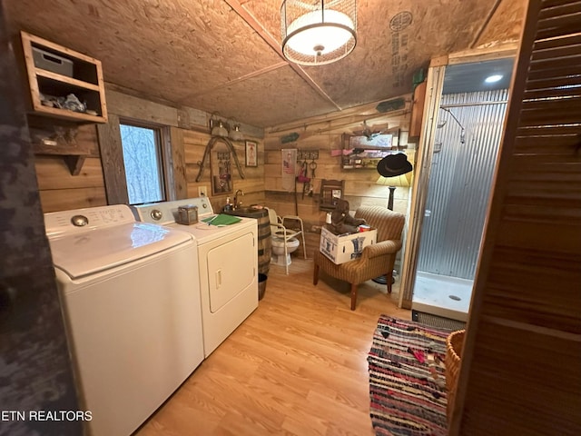 laundry room with washing machine and dryer, wood walls, and light hardwood / wood-style floors