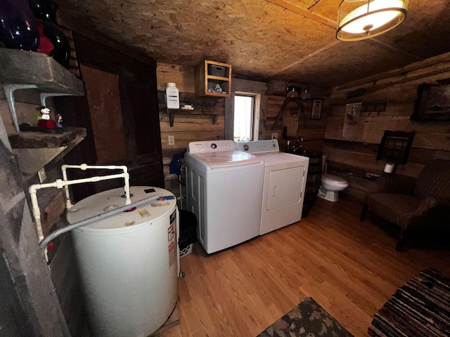 laundry area featuring hardwood / wood-style floors, log walls, wooden walls, and washing machine and dryer