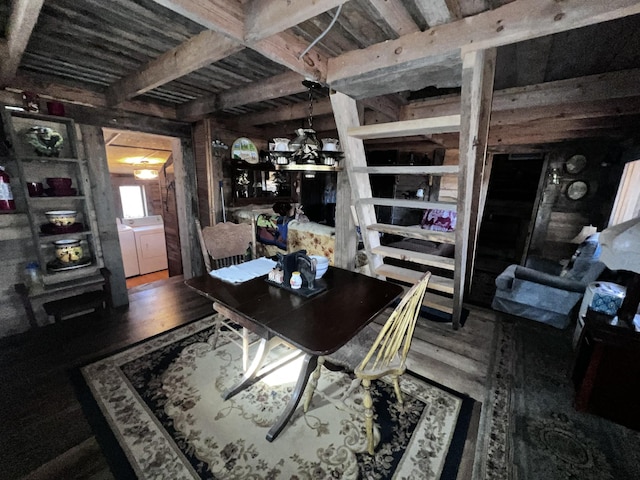 dining space with hardwood / wood-style floors, wood walls, beamed ceiling, separate washer and dryer, and a notable chandelier