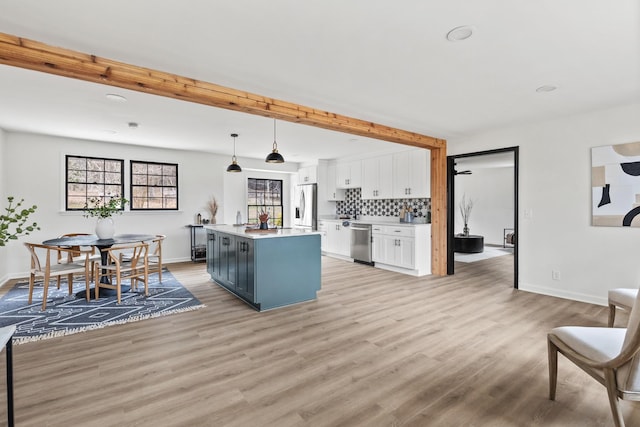 kitchen featuring a center island, decorative backsplash, appliances with stainless steel finishes, decorative light fixtures, and white cabinetry