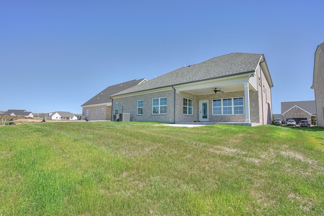 rear view of house featuring ceiling fan and a lawn