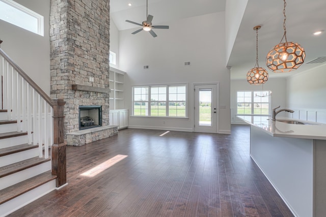 unfurnished living room with dark hardwood / wood-style floors, a fireplace, ceiling fan with notable chandelier, and high vaulted ceiling