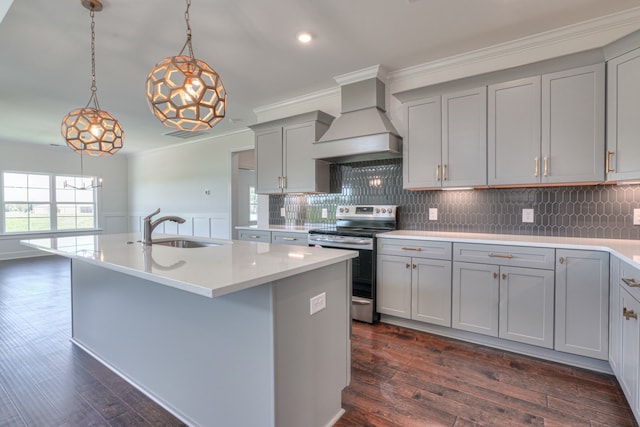 kitchen with decorative light fixtures, sink, stainless steel range with electric cooktop, custom exhaust hood, and a center island with sink