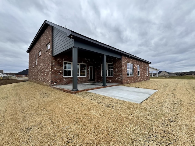 back of property with a patio area and brick siding