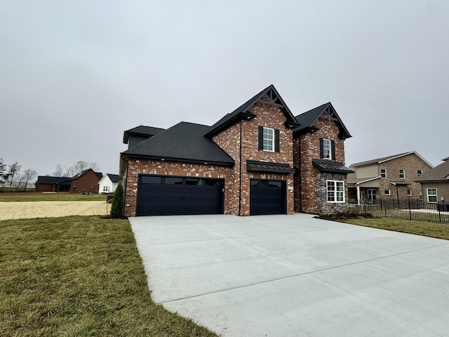 view of front of home with a shingled roof, concrete driveway, fence, a front yard, and brick siding