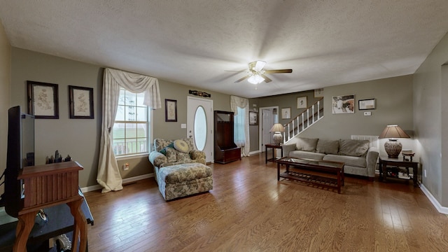 living room with hardwood / wood-style floors, ceiling fan, and a textured ceiling