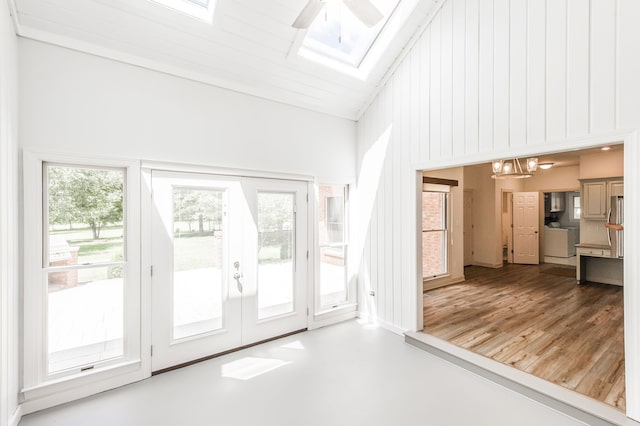 doorway with ceiling fan with notable chandelier, wood-type flooring, french doors, and lofted ceiling with skylight