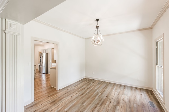 spare room featuring light hardwood / wood-style floors, crown molding, and a notable chandelier