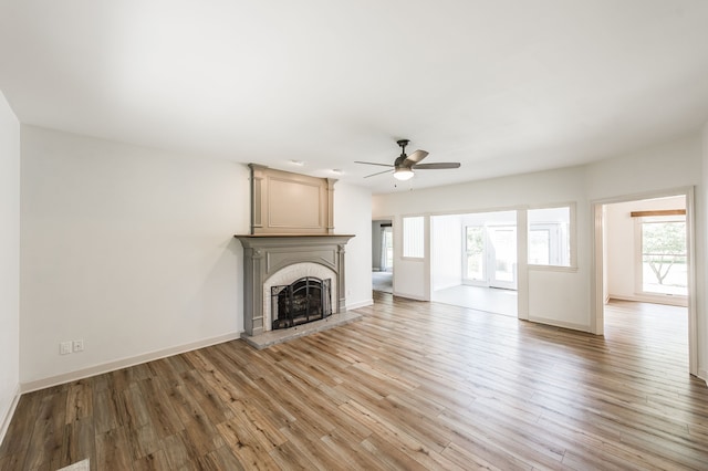 unfurnished living room featuring ceiling fan, light wood-type flooring, and a fireplace