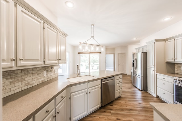 kitchen featuring sink, stainless steel appliances, tasteful backsplash, pendant lighting, and light wood-type flooring