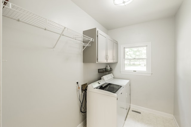 laundry area with separate washer and dryer and cabinets