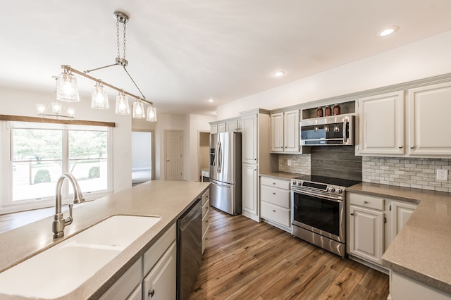 kitchen featuring sink, dark hardwood / wood-style floors, appliances with stainless steel finishes, tasteful backsplash, and decorative light fixtures