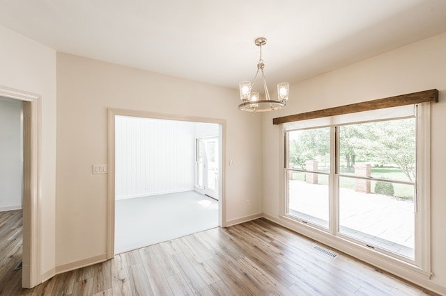 unfurnished dining area with a chandelier and light hardwood / wood-style floors