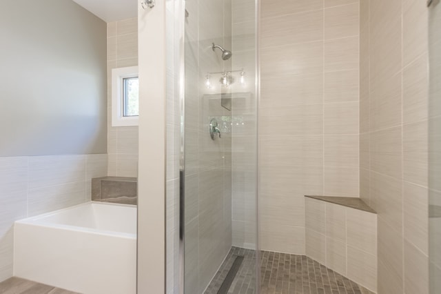 bathroom with tile walls and shower with separate bathtub