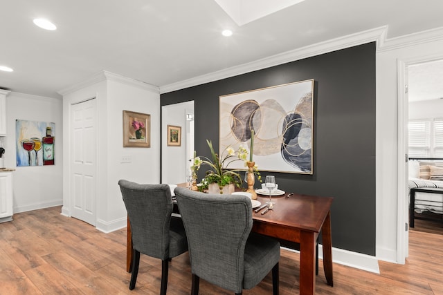 dining area with crown molding and light hardwood / wood-style flooring