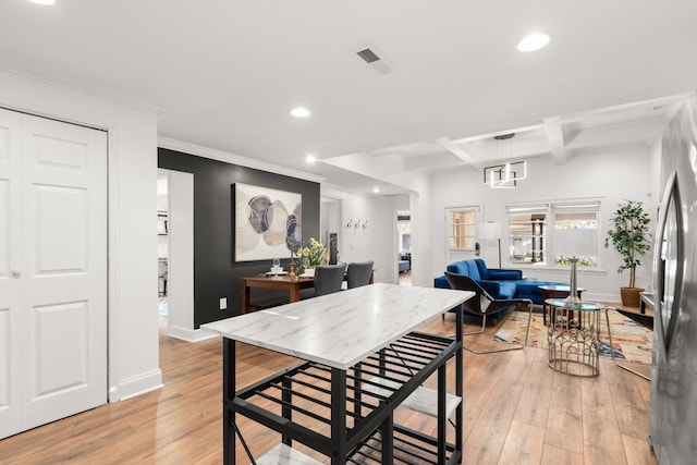 dining space with beam ceiling, light hardwood / wood-style floors, coffered ceiling, and ornamental molding