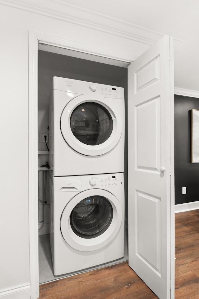 washroom with crown molding, wood-type flooring, and stacked washer / drying machine