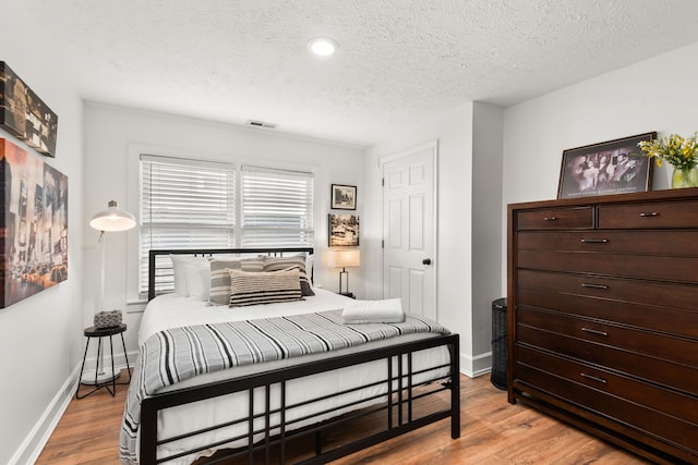 bedroom with a textured ceiling and light hardwood / wood-style floors