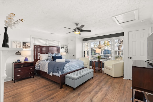 bedroom with a textured ceiling, ceiling fan, ornamental molding, and dark wood-type flooring