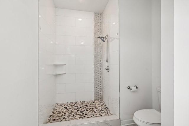 bathroom with tiled shower and toilet