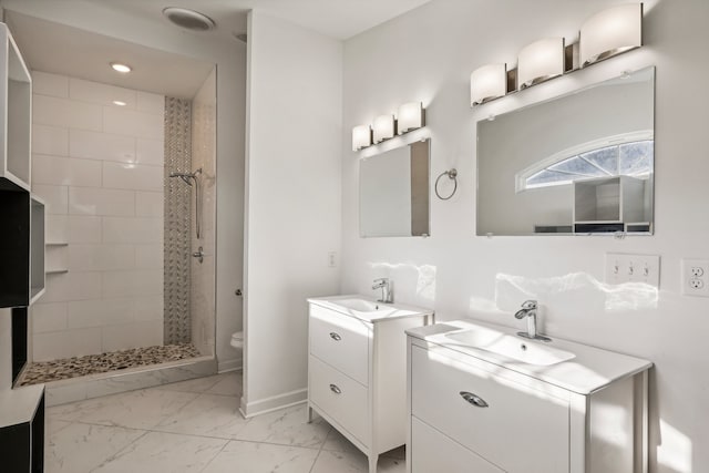 bathroom with tiled shower, vanity, and toilet