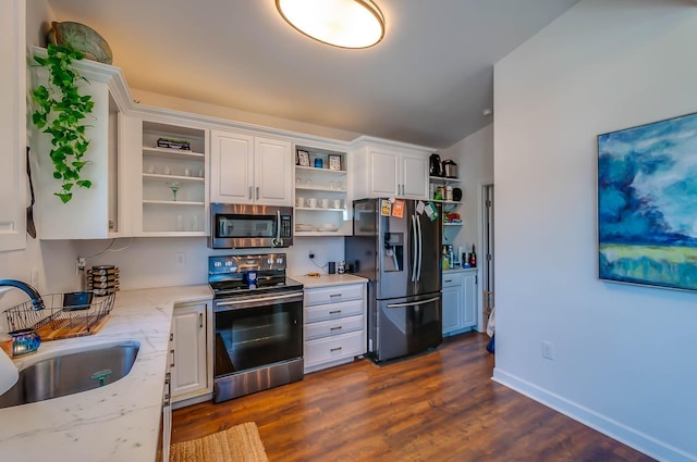 kitchen with appliances with stainless steel finishes, light stone counters, white cabinetry, and sink