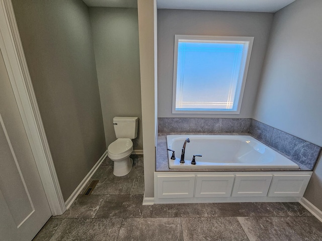 bathroom with a tub to relax in and toilet