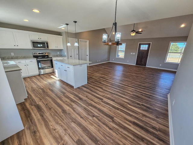 kitchen featuring dark wood-type flooring, white cabinetry, a center island, hanging light fixtures, and appliances with stainless steel finishes