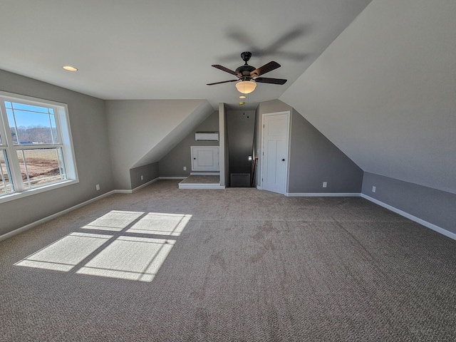 additional living space with lofted ceiling, light colored carpet, an AC wall unit, and ceiling fan