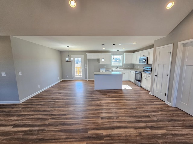 kitchen with a kitchen island, pendant lighting, white cabinetry, stainless steel appliances, and dark wood-type flooring