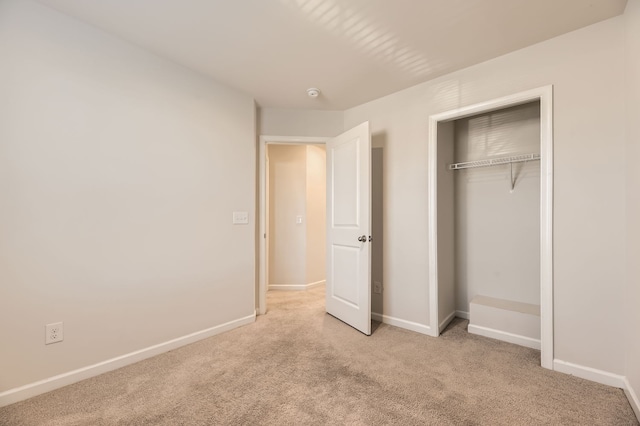 unfurnished bedroom featuring a closet and light colored carpet