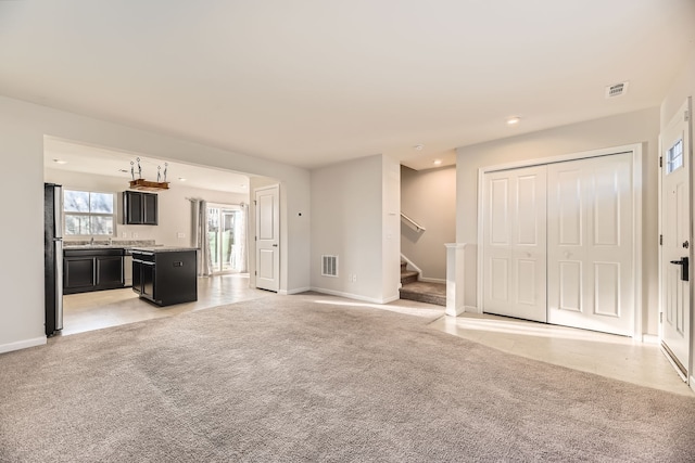 unfurnished living room featuring light colored carpet