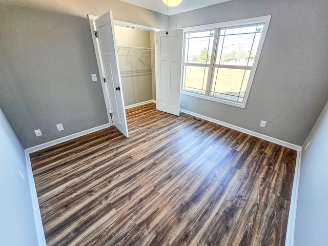 unfurnished bedroom with dark hardwood / wood-style floors and a closet