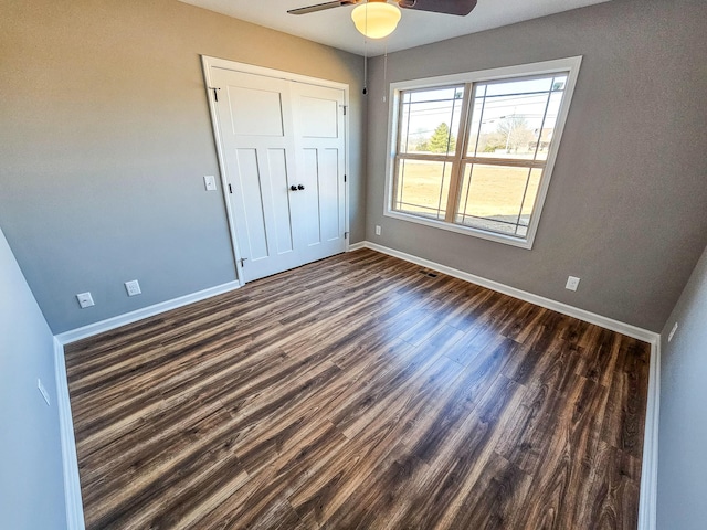 unfurnished bedroom featuring dark wood-type flooring, ceiling fan, and a closet