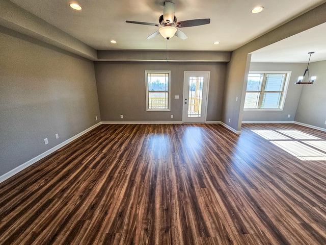 unfurnished room featuring dark wood-type flooring and ceiling fan with notable chandelier