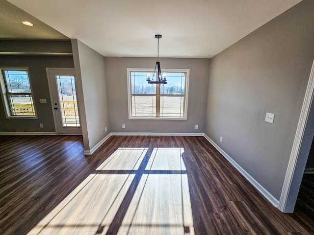 unfurnished dining area with an inviting chandelier and dark hardwood / wood-style flooring